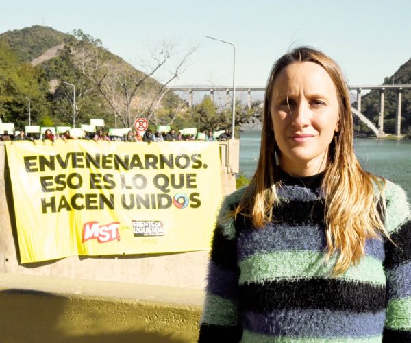 Luciana Echevarría frente al embudo del lago San Roque con un cartel que dice Envenenarnos es lo que hacen unidos