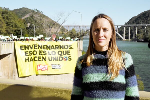 Luciana Echevarría en el embudo del lago San Roque con un cartel de fodo que dice: "Envenenarnos, eso es lo que hacen unidos"
